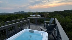 A hot tub on a wooden deck with a view of a mountainous landscape.