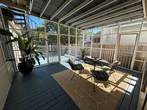 A covered patio with a wooden deck, outdoor furniture, and potted plants.