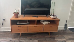 Puisesta materiaalista valmistettu viihdekeskus, jossa on litteänäyttöinen televisio, kaukosäädin, ruukkukasvi ja koristeellinen kulho.