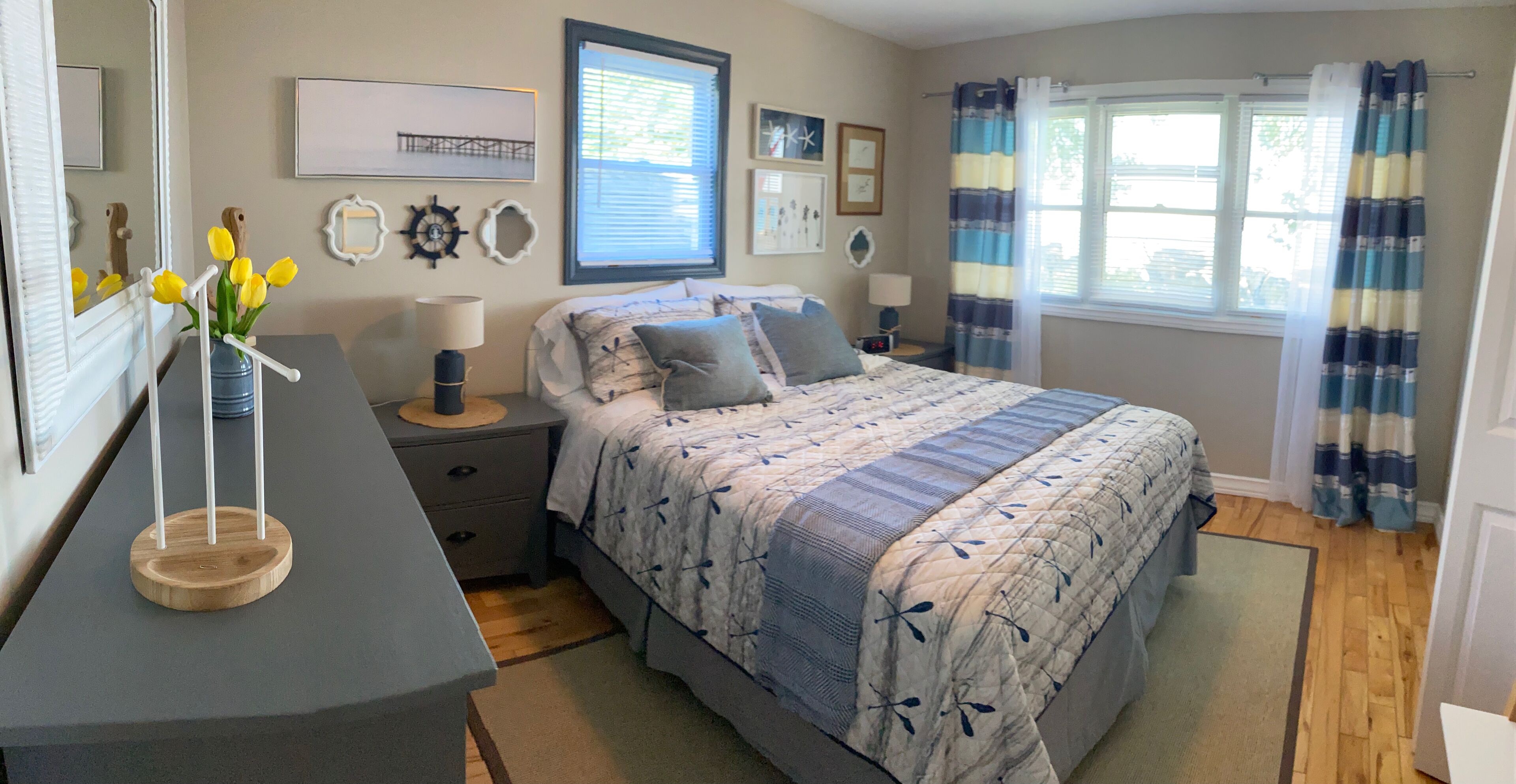 A bedroom with a bed, nightstands, a dresser, a mirror, and a window with curtains.