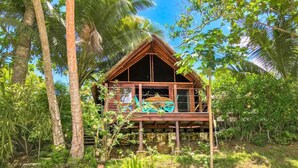 A wooden cabin with a balcony, surrounded by lush greenery and palm trees. - Freshwater Private Resort (Aore Island)