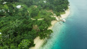 An aerial view of a coastal area with a beach, dense greenery, and a few buildings. - Freshwater Private Resort (Aore Island)