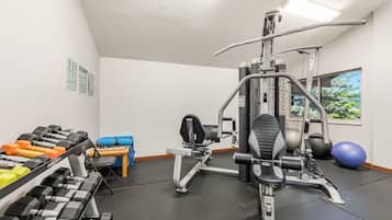 Ein Fitnessraum mit Trainingsgeräten, Kurzhanteln und einem blauen Trainingsball.