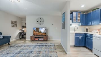 A modern living room with a flat-screen TV, a blue sofa, and a patterned rug.