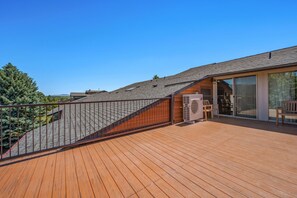 A wooden deck with a glass door leading to a covered outdoor area.