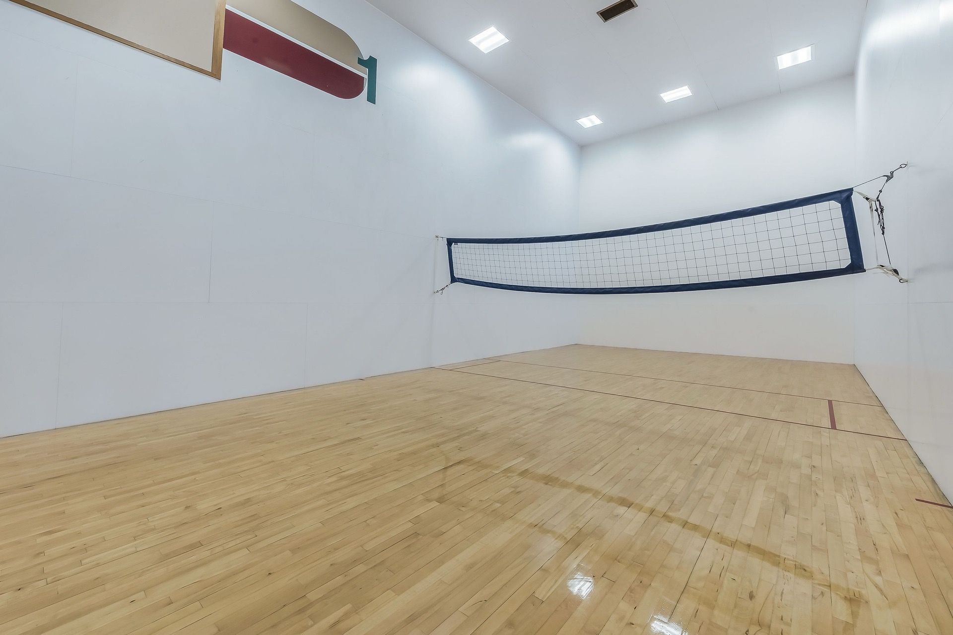Una cancha de squash con piso de madera y una red.