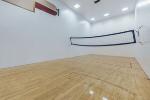 A squash court with a wooden floor and a net.