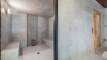 A modern bathroom with a shower, a bench, and a patterned wall.