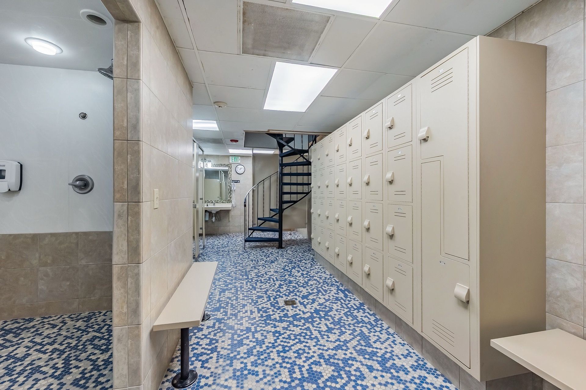 A hallway with lockers, a sink, and a patterned floor.