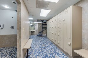 A hallway with lockers, a sink, and a patterned floor.