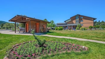 A building with a covered outdoor area, a playground, and a flower garden.