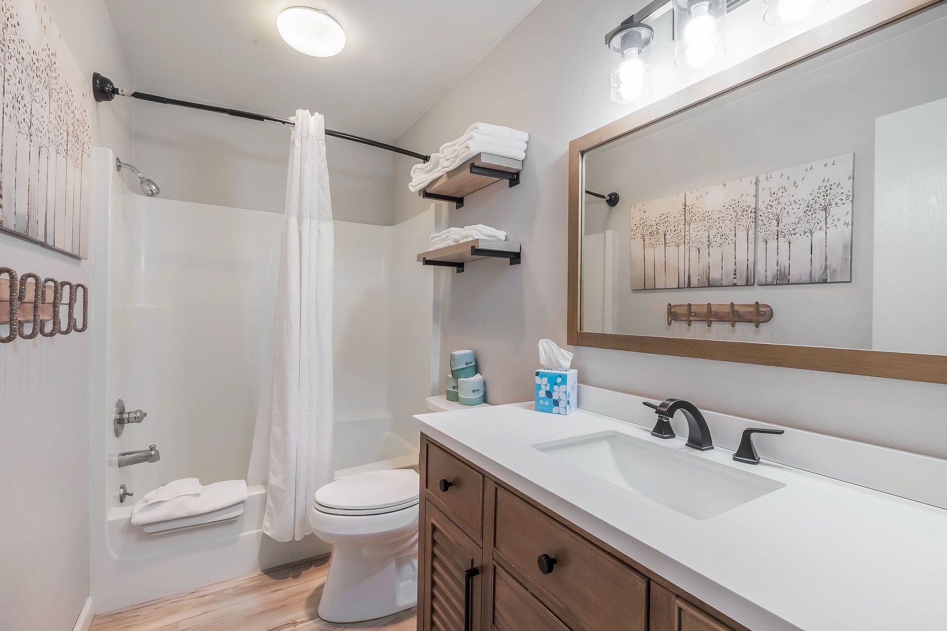 Un baño moderno con ducha, inodoro, tocador y un espejo grande.