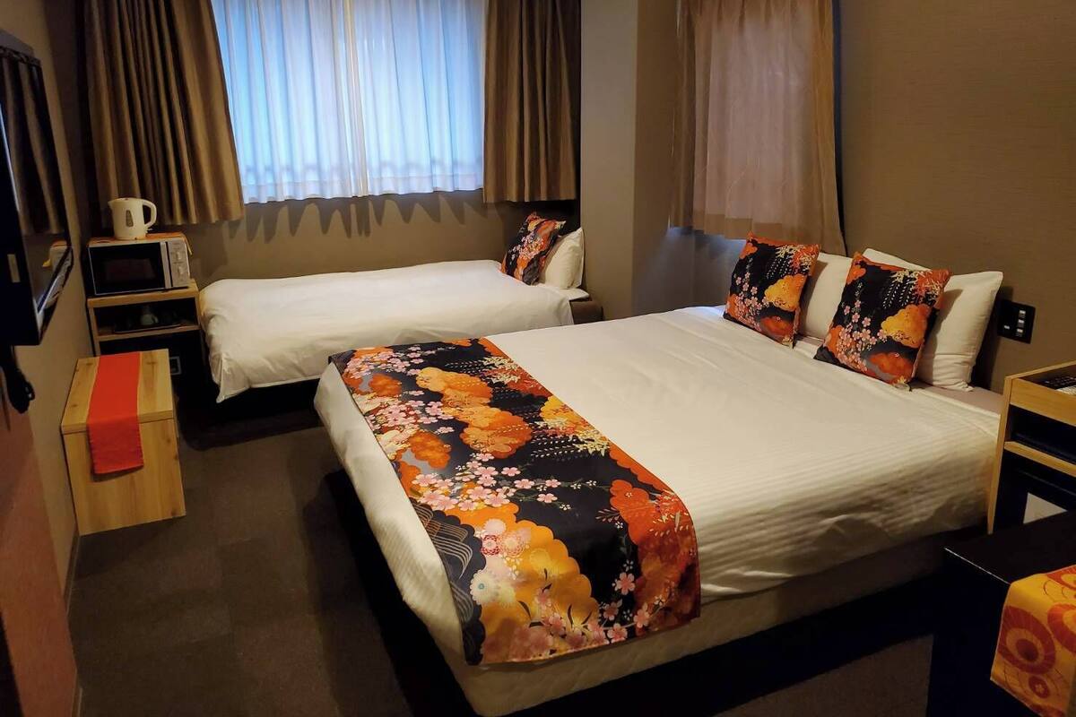 Een hotelkamer met twee bedden, een magnetron, een klein tafeltje en een televisie.