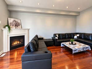 A modern living room with a fireplace, leather sofas, and a coffee table.