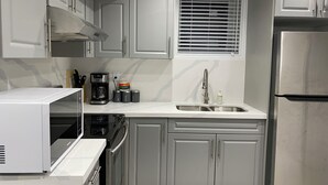 Una cocina moderna con armarios grises, un refrigerador de acero inoxidable, una cafetera y un microondas.