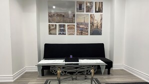 Una habitación con un sofá negro, una mesa de vidrio y un elegante soporte de metal.