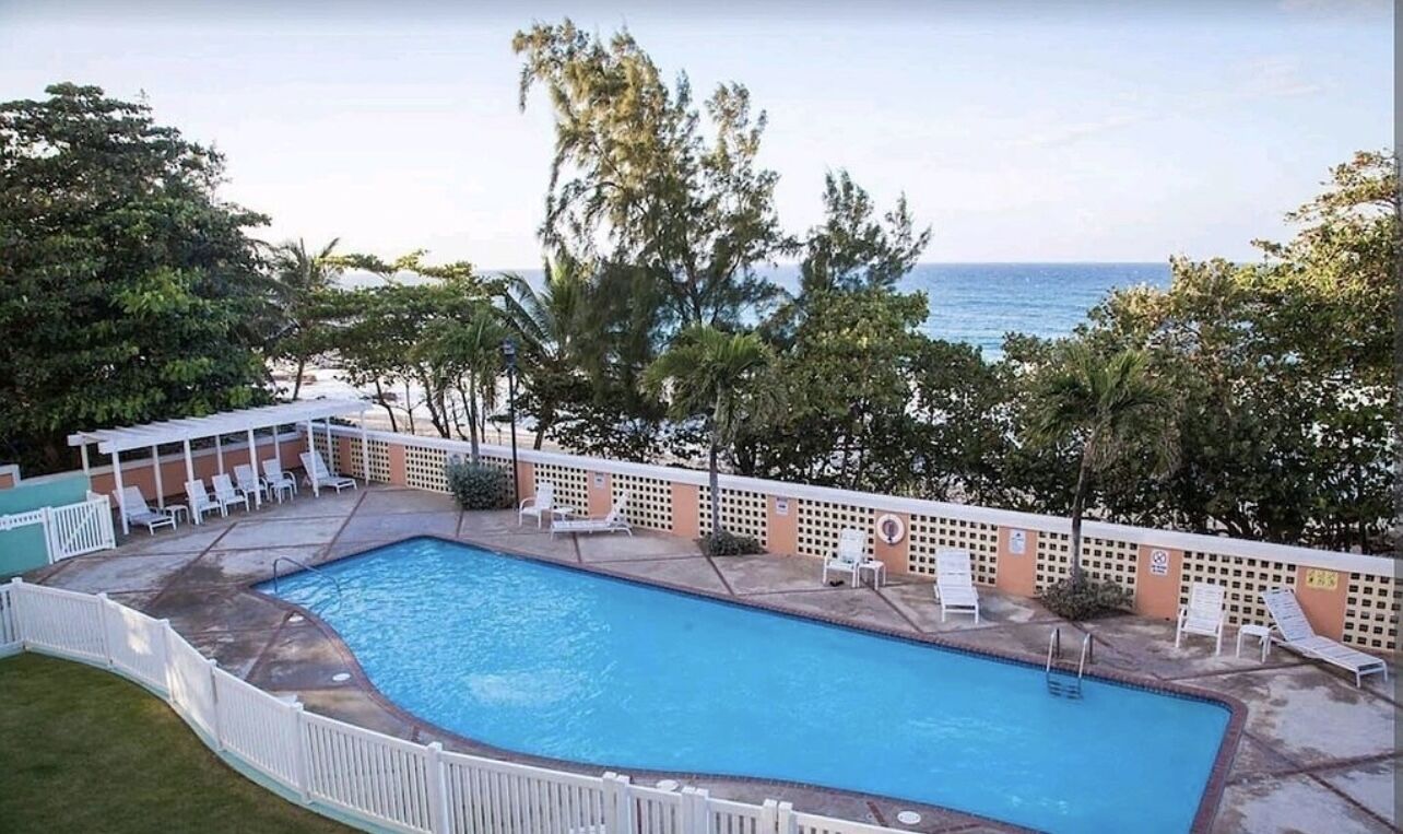 A swimming pool with lounge chairs and a view of the ocean.