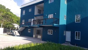 A multi-story building with balconies, a staircase, and a gated entrance. - Stylish 1 Bedroom Beach view (Belmont)