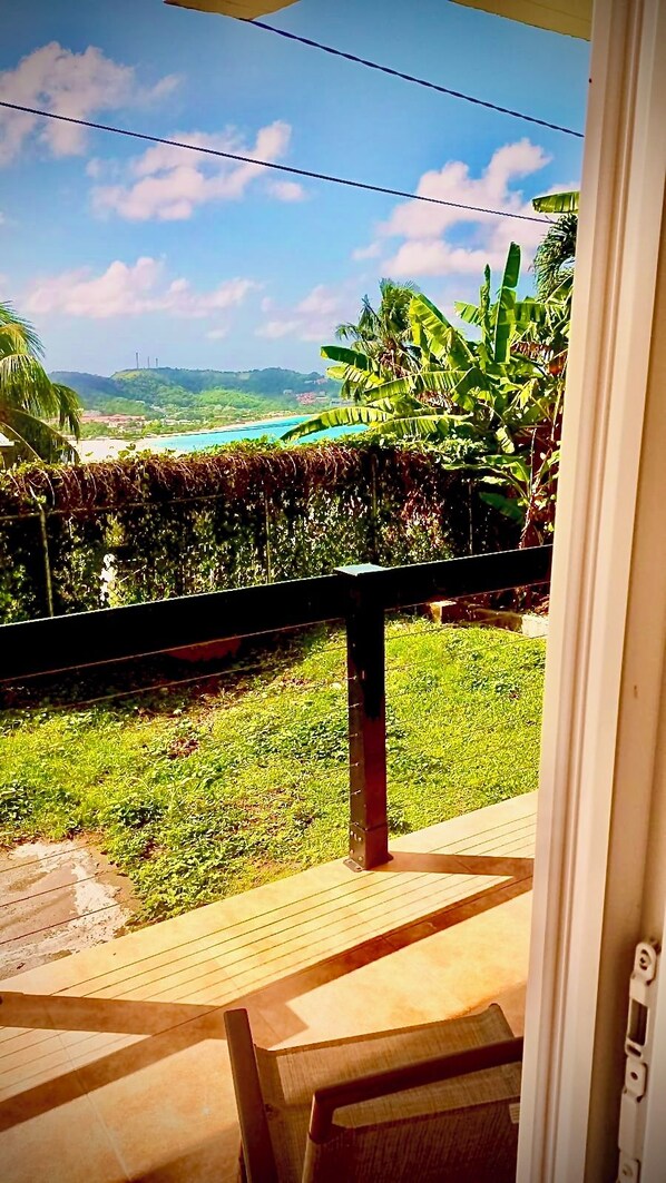 A view from a balcony with a wooden floor, a metal railing, and a clear sky. - Stylish 1 Bedroom Beach view (Belmont)