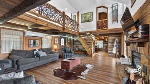 Un vaste espace de vie agrémenté d’un escalier en bois, d’une cheminée et d’une grande fenêtre.