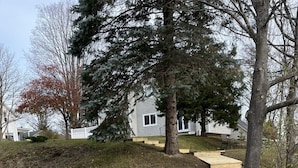 A wooden pathway leading to a house surrounded by trees. - Feet from Lake & Downtown, Pond View, Hot Tub,Pets (Northport)