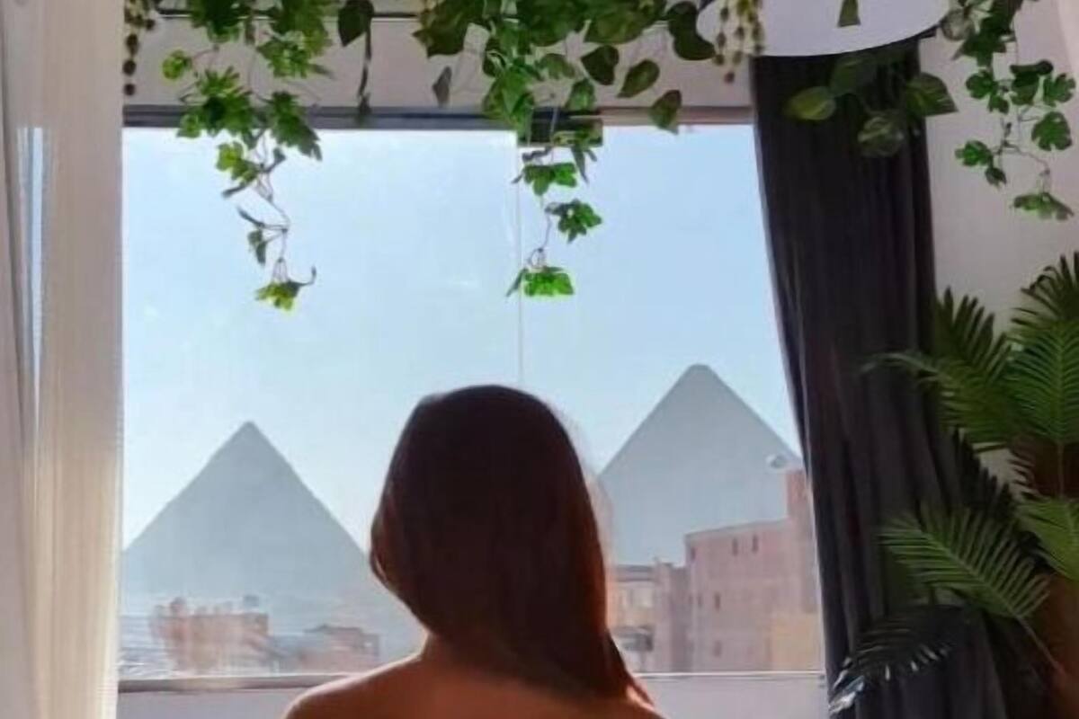Una persona sentada en una cama con vistas a las pirámides.