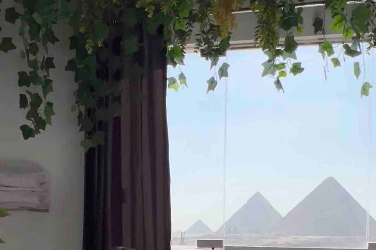 Une chambre avec vue sur les pyramides, une fenêtre avec des rideaux et un lavabo.