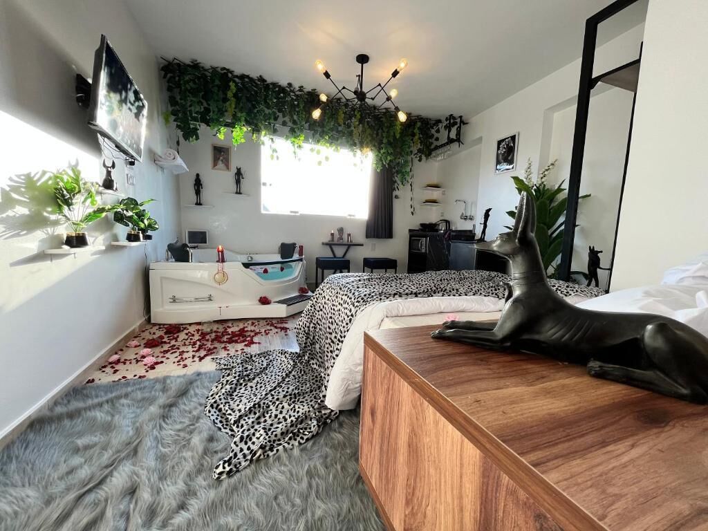 Quarto moderno com penteadeira de madeira, colcha com estampa de leopardo e um espelho grande.