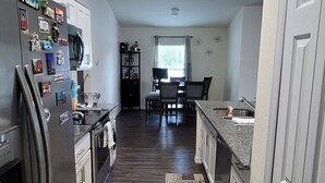 A modern kitchen with stainless steel appliances, a dining area with a table and chairs, and a patterned rug on the floor.