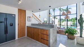 A modern kitchen with a wooden island, black refrigerator, and pendant lights. - Villa Vybe (Canggu)