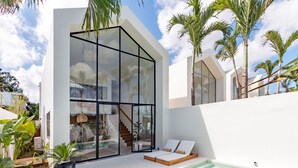 A modern house with a glass facade, a pool, and a staircase leading to the interior. - Villa Vybe (Canggu)