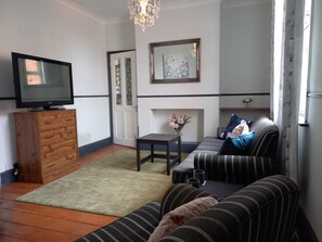 A living room with a television, wooden cabinet, sofa, and a fireplace.