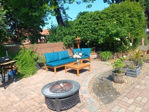 A patio with a fire pit, wooden furniture, and potted plants.