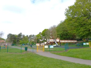 A playground with a fenced area, a slide, and a climbing structure.
