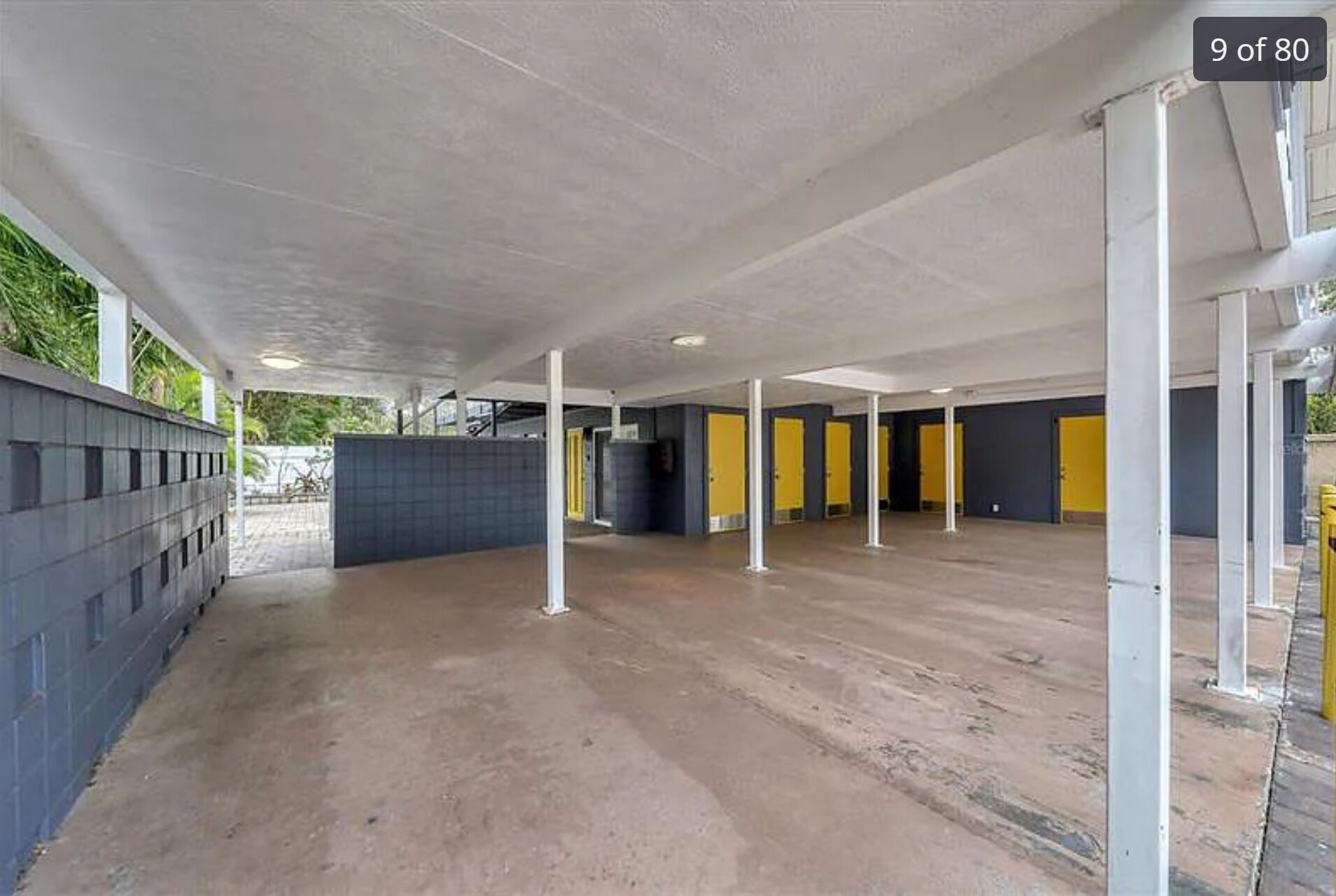 An indoor covered parking area with concrete floors and yellow doors.