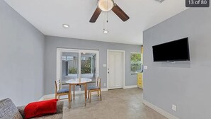 A spacious living area with a ceiling fan, a flat-screen TV mounted on the wall, and a sliding glass door leading to a patio.