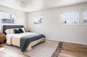 Une chambre à coucher avec un lit, une table de chevet, un tapis et une fenêtre.