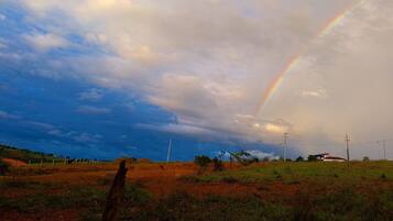 A rural landscape with a rainbow, power lines, and a dirt road.