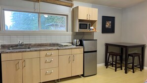 A kitchen with a granite countertop, stainless steel appliances, wooden cabinets, and a window with blinds.