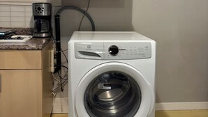 A compact kitchen with a microwave, a coffee maker, and a washing machine.