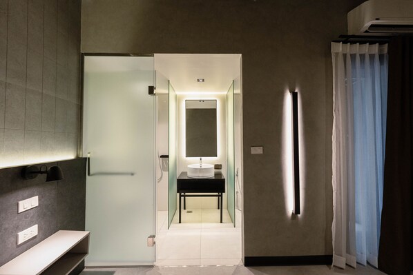 A modern bathroom with a glass-enclosed shower, a white sink, and a mirror above it.