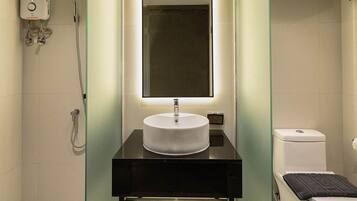 A modern bathroom with a round sink, a handheld showerhead, and a toilet.