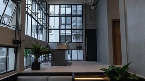 A modern lobby with a seating area, a staircase, and large windows. - EXII Hotel Ngamwongwan (Nonthaburi)