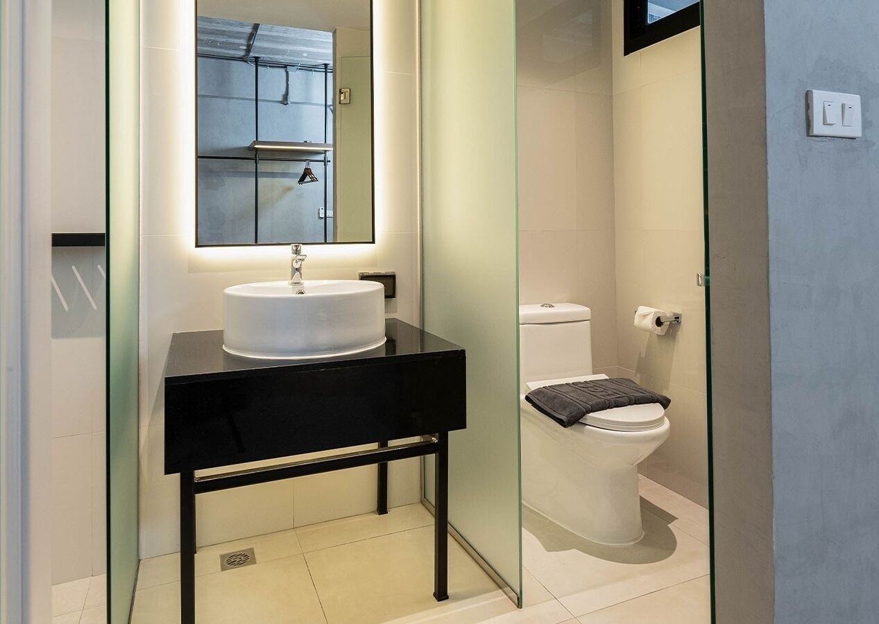 Ein modernes Badezimmer mit einem runden weißen Waschbecken, einer schwarzen Arbeitsplatte und einer Duschkabine aus Glas.