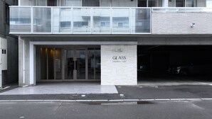 A modern building with a glass facade, a stone-textured entrance, and a sign that reads "GLASS." - GLASS YAMAHANA EAST (Sapporo)