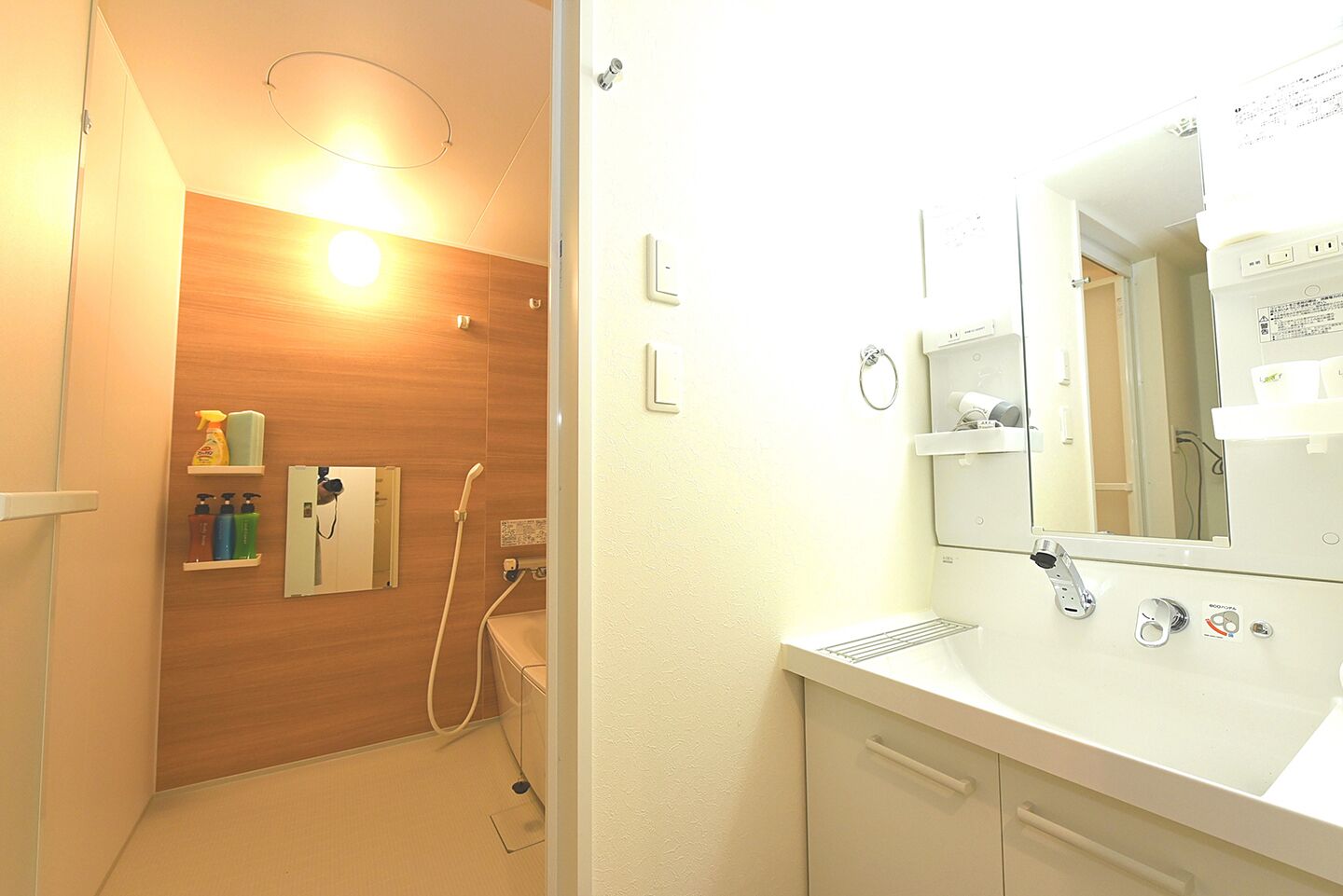 A bathroom with a wooden vanity, a mirror, a sink, and a shower area.