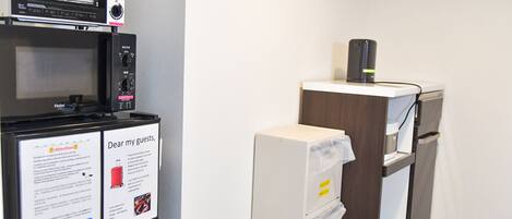 A hotel room with a microwave, a coffee machine, and a minibar. There is also a notice for guests.