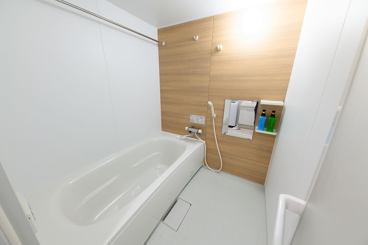 A modern bathroom with a white bathtub, wooden panel wall, and a small shelf with toiletries.