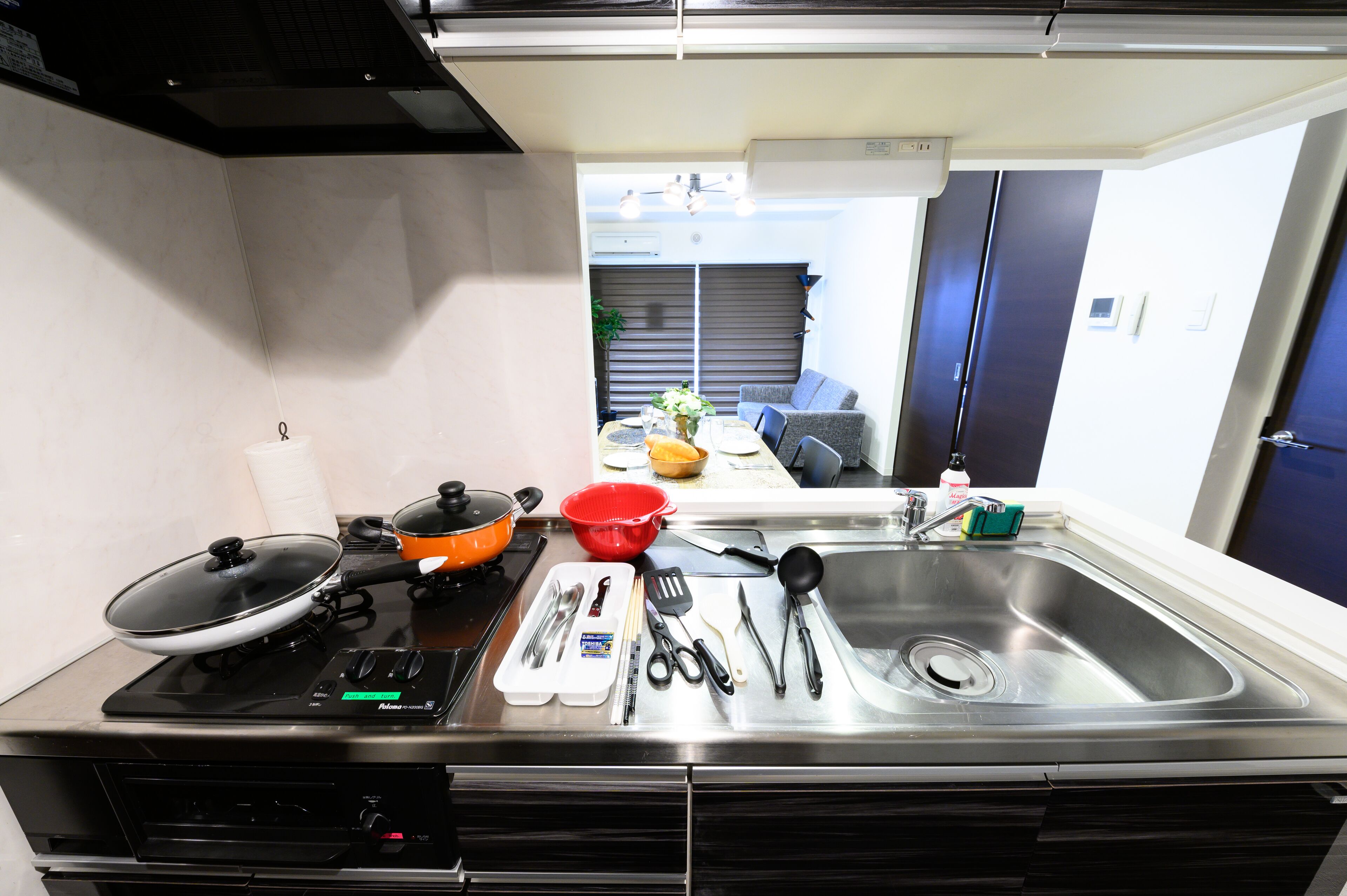 Una cocina con estufa, fregadero y diversos utensilios.