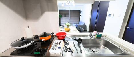 Una cocina con estufa, fregadero y diversos utensilios.